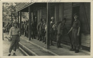 A Cameronian soldier stands guard as a queue of Japanese prisoners await processing.